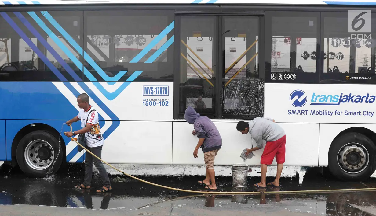 Suporter Persija Jakarta mencuci bus transjakarta di kantor PT Transjakarta, Jakarta, Kamis (13/12). Hal tersebut dilakukan bentuk tanggung jawab atas aksi vandalisme oknum suporter saat Persija meraih Juara Liga 1 2018. (Liputan6.com/Immanuel Antonius)