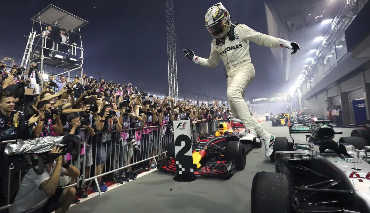 Pebalap Mercedes, Lewis Hamilton merayakan kemenangan saat menjuarai F1 Singapura di  Marina Bay City Circuit, (17/9/2017).  (AP/Yong Teck Lim)