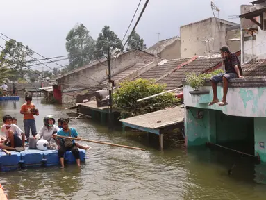 Warga melintas dengan perahu buatan saat banjir melanda perumahan Periuk Damai, Tangerang, Banten, Selasa (22/2/2021). Banjir setinggi 2,5 meter tersebut sudah terjadi selama 4 hari. (Liputan6.com/Angga Yuniar)