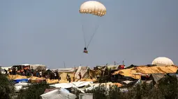 Terlihat benda-benda dengan parasut berjatuhan menuju ke tenda pengungsian warga Palestina. (Eyad BABA / AFP)