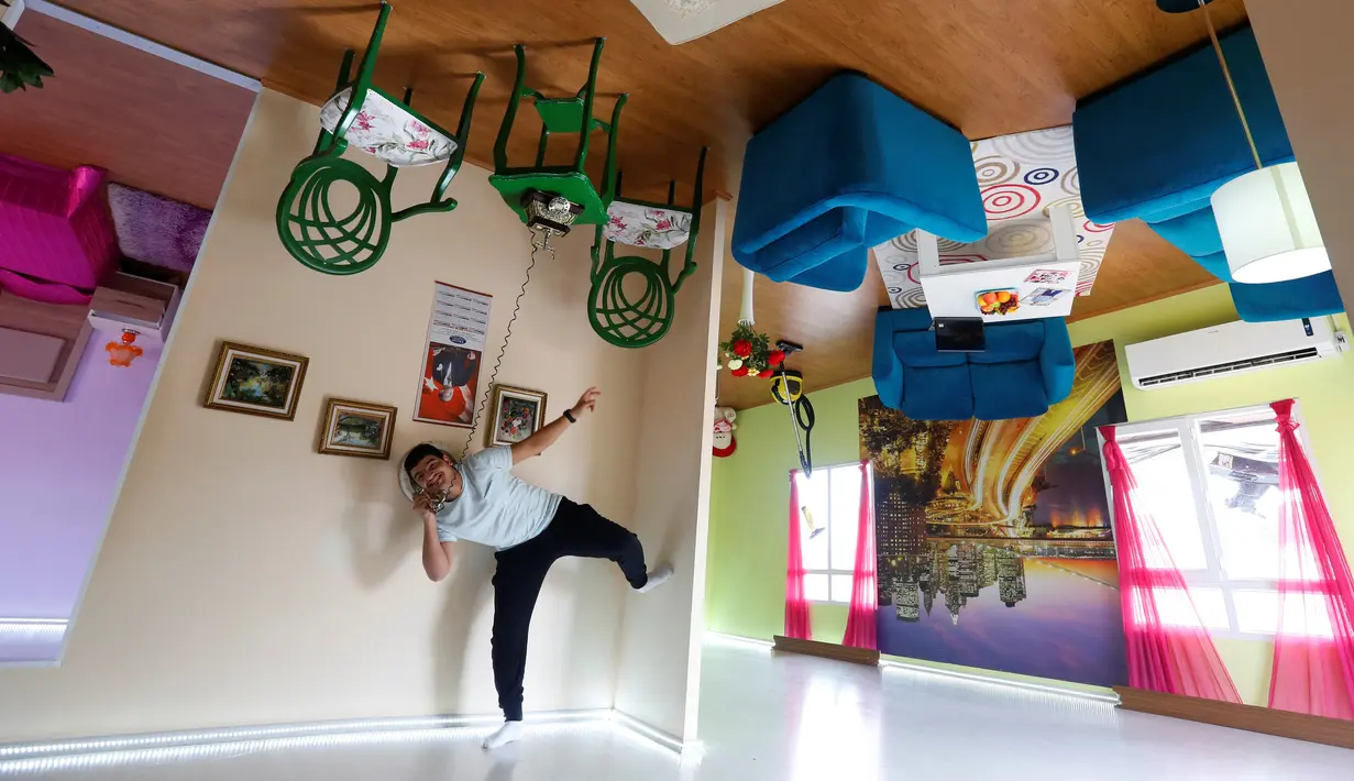 Seorang turis memegang telepon saat berkunjung ke dapur rumah terbalik di kota resor Mediterania, Antalya, Turki, Sabtu (12/11). Keberadaan rumah terbalik ini menjadi daya tarik tersendiri untuk wisatawan. (REUTERS/Murad Sezer)