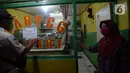 Petugas menempelkan stiker perautran "Take away"  di tempat makan di wilayah Kecamatan Pulogadung, Jakarta, Jumat (18/9/2020). Malam, Razia dilakukan memastikan ketidakadaannya konsumen makan ditempat tersebut. (merdeka.com/Imam Buhori)