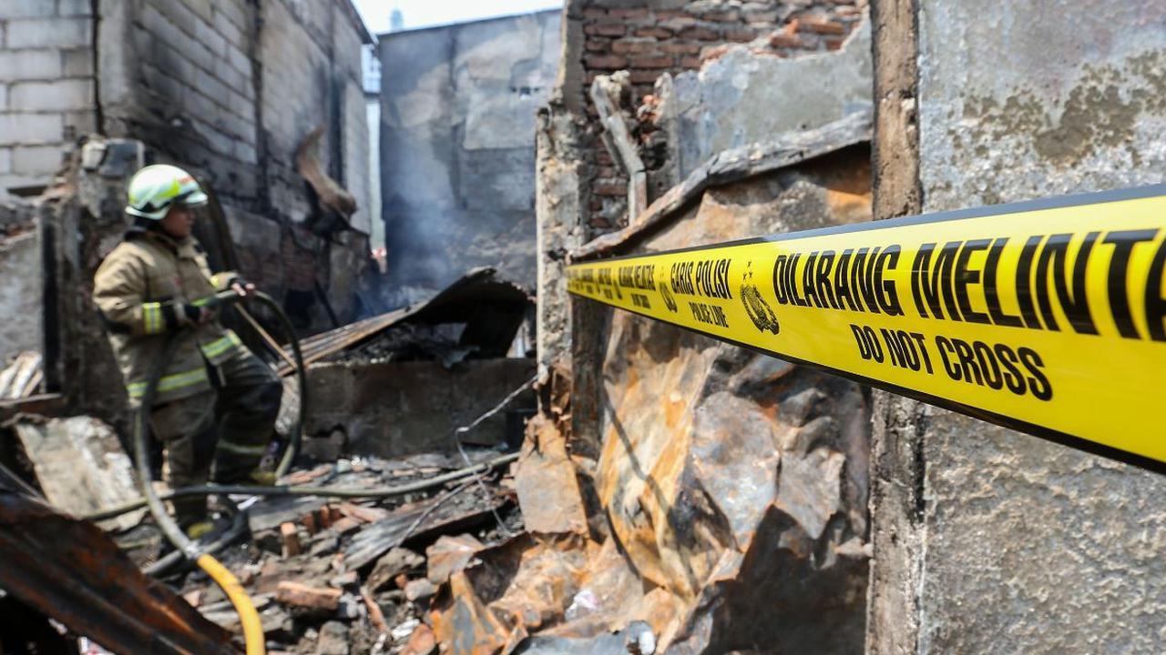 Garis kuning 'dilarang melintas' tampak sudah terpasang saat petugas pemadam kebakaran melakukan pendinginan pada lokasi kebakaran di kawasan permukiman padat penduduk di Petojo Selatan, Jakarta, Kamis (24/8/2023).