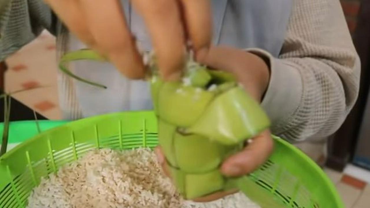 Saat beras sudah benar-benar kering, kita bisa mulai memasukkannya ke dalam anyaman daun kelapa muda.