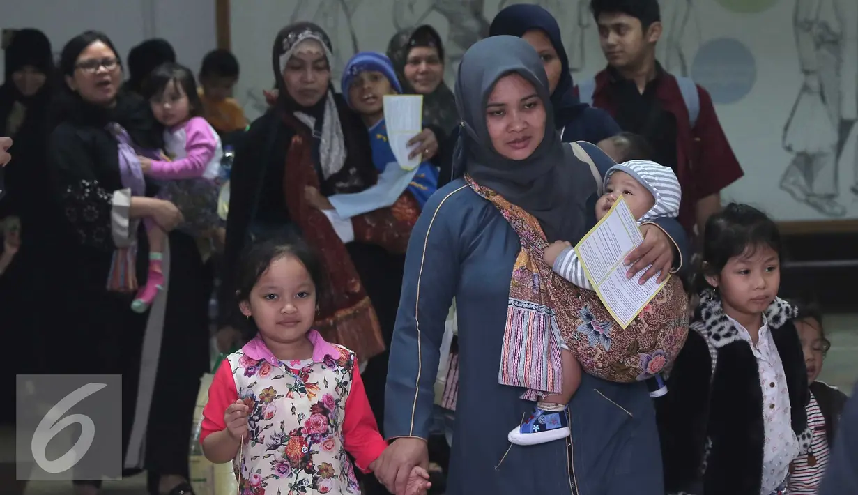 Seorang TKI bersama anaknya tiba di Bandara Soekarno Hatta,Tangerang, Rabu (11/11). Sebanyak 450 WNI overstayers dan TKI undocumented dari Jeddah, Arab Saudi dipulangkan pemerintah Indonesia untuk kembali ke kampung halaman. (Liputan6.com/Angga Yuniar)