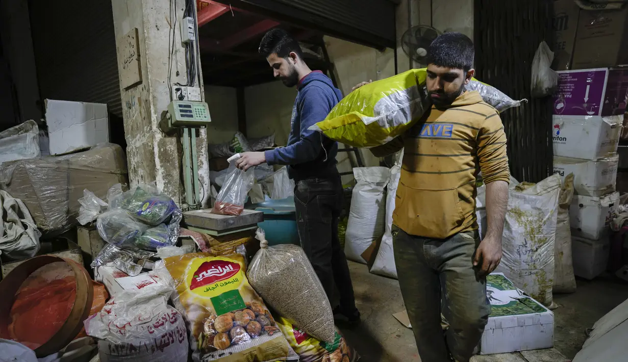 Seorang penjaga toko menimbang barang dagangan di pasar utama Shurja di pusat Baghdad, Irak, pada 22 Maret 2022. Melonjaknya harga energi dan makanan yang dipicu oleh invasi Rusia ke Ukraina mendorong beberapa negara Timur Tengah ke tepi jurang.  (AP Photo/Hadi Mizban)