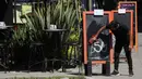 Seorang pelayan menghapus papan pengumuman minuman spesial untuk menggantikannya dengan makanan spesial di bar dan restoran kosong di Mexico City (23/3/2020). (AP Photo/Fernando Llano)