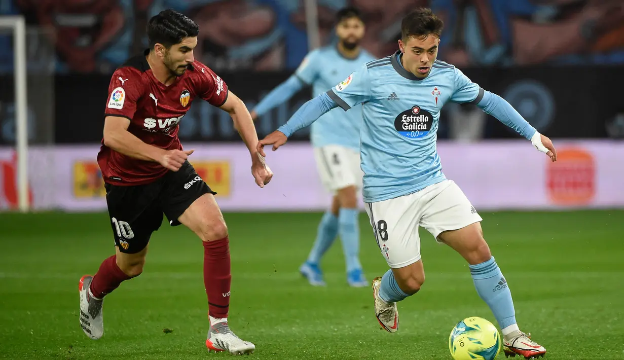 Pemain Valencia Carlos Soler (kiri) berebut bola dengan pemain Celta Vigo Fran Beltran pada pertandingan Liga Spanyol di Stadion Balaidos, Vigo, Spanyol, 5 Desember 2021. Valencia menang 2-1. (MIGUEL RIOPA/AFP)