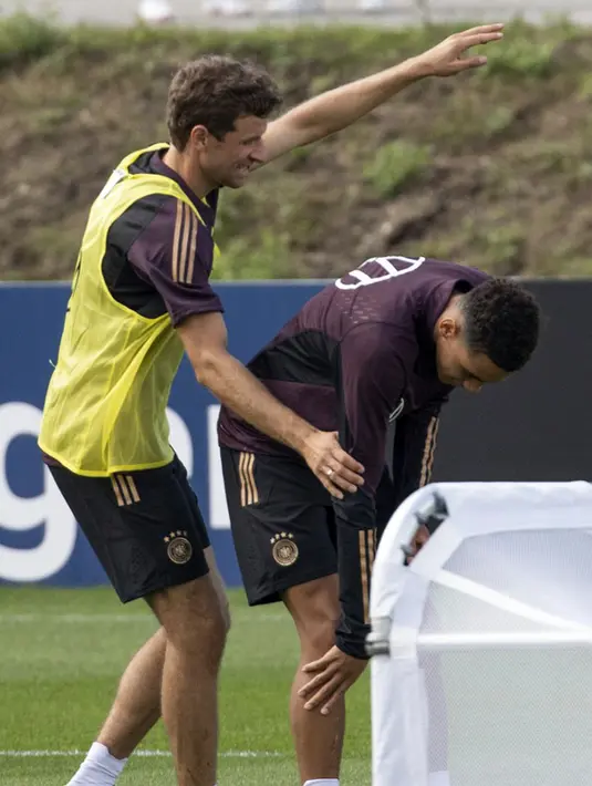 Pemain Jerman Thomas Mueller (kiri) menghibur Jamal Musiala yang sedang memeriksa kakinya karena cedera saat sesi latihan di Kampus DFB, Frankfurt, Jerman, Selasa (20/9/2022). Jerman akan menghadapi Hungaria pada pertandingan sepak bola Grup 3 UEFA Nations League. (ANDRE PAIN/AFP)