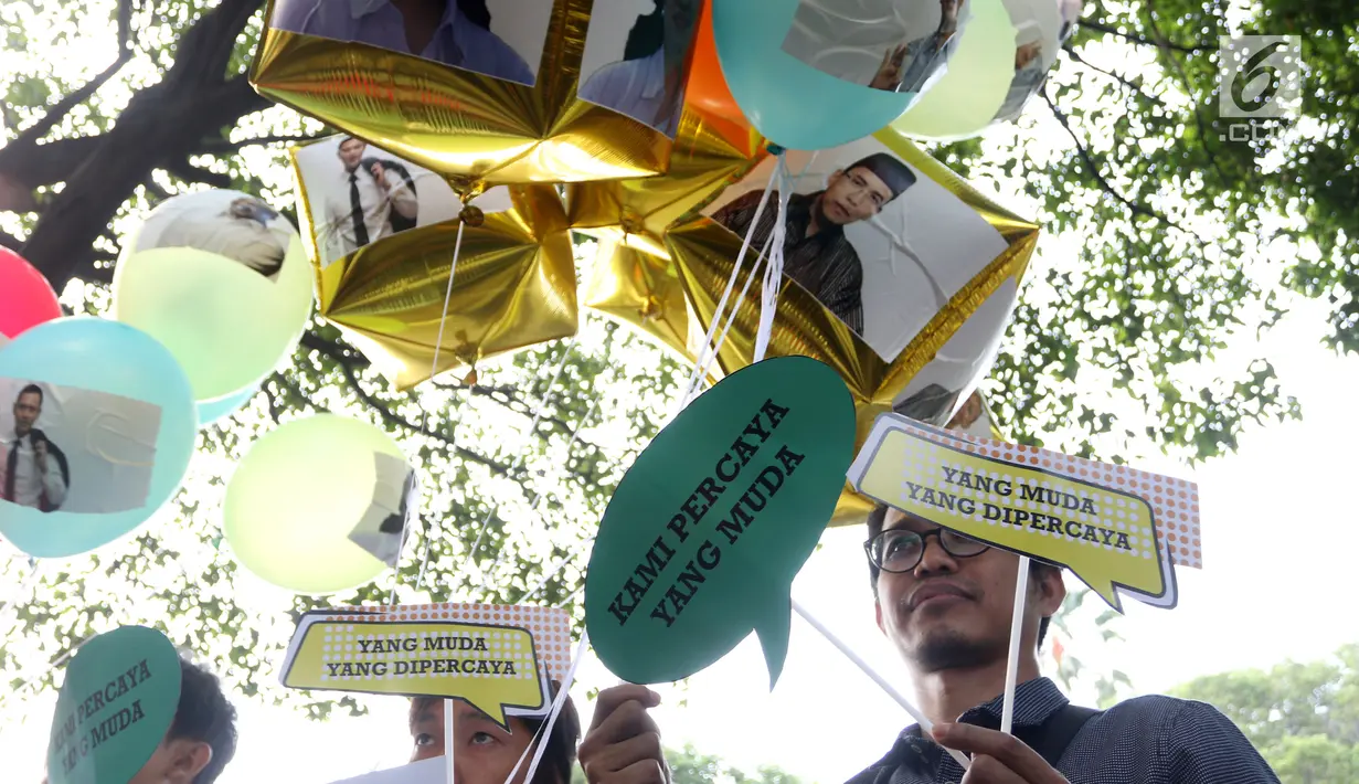 Aktivis Poros Indonesia Muda melakukan aksi pelepasan balon bertempelkan gambar politisi muda Indonesia di Gedung KPU, Jakarta, Rabu (1/8). Mereka berharap Pemilu 2019 mendapatkan pilihan yang membawa aspirasi kaum muda. (Liputan6.com/Helmi Fithriansyah)