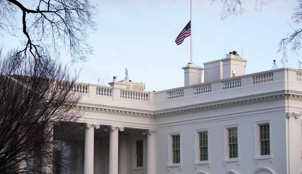 Gedung Putih mengibarkan Bendera Amerika setengah tiang untuk menandai 500.000 kematian akibat Covid-19 di Washington D.C. pada Senin (22/2/2021). Presiden Joe Biden memerintahkan agar bendera AS di properti federal diturunkan menjadi setengah tiang selama lima hari. (SAUL LOEB/AFP)