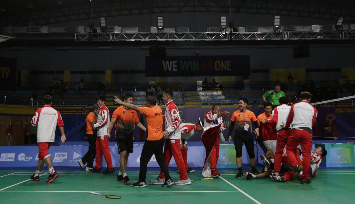 Pemain dan pelatih tim beregu putra Indonesia merayakan gelar juara cabang bulutangkis SEA Games 2019 di Multinlupa Sport Center, Rabu (4/12). Indonesia meraih emas setelah menang 3-1 atas Malaysia. (Bola.com/M Iqbal Ichsan)