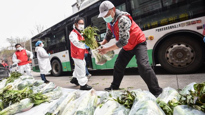 Sukarelawan membagikan kantong berisi sayuran di Wuhan, Provinsi Hubei, 13 Maret 2020. (dok. STR / AFP)