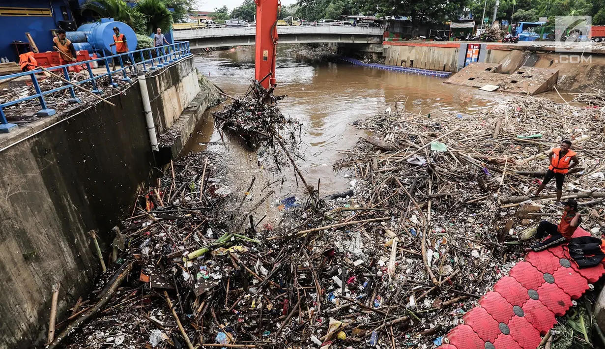 Sebuah eskavator mengangkat tumpukan sampah di Pintu Air Manggarai Jakarta, Senin (12/11). Hujan deras yang mengguyur pada Minggu malam membuat sampah yang terbawa arus Kali Ciliwung menutupi Pintu Air Manggarai. (Liputan6.com/Fery Pradolo)