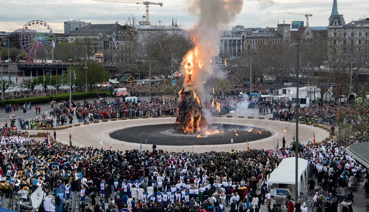 Warga menonton boneka salju raksasa atau yang disebut Boeoegg yang dibakar di alun-alun Sechselaeuten, Zurich, Swiss (16/4). (Ennio Leanza/Keystone via AP)