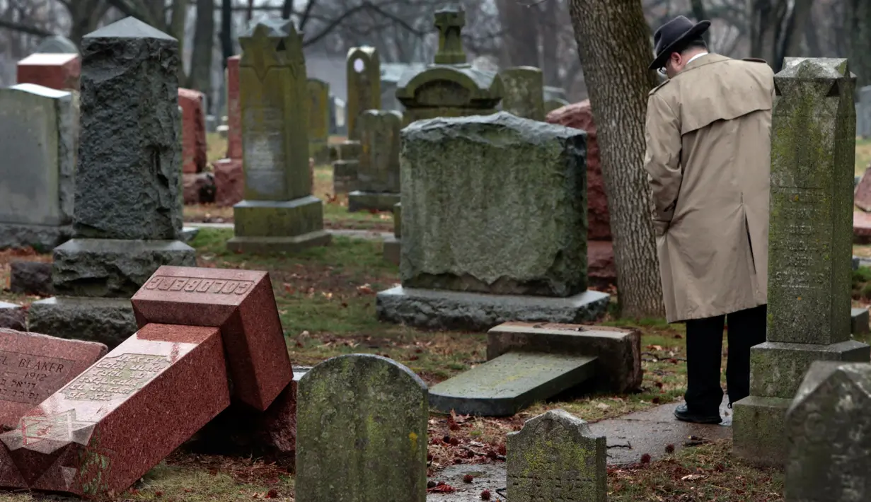  Warga melihat batu nisan Yahudi yang rusak usai serangan vandalisme di Chesed Shel Emeth Cemetery di University City, St Louis, Missouri, (21/2). Setidaknya lebih dari 100 batu nisan rusak di pekuburan itu. (Robert Cohen /St. Louis Post-Dispatch via AP)
