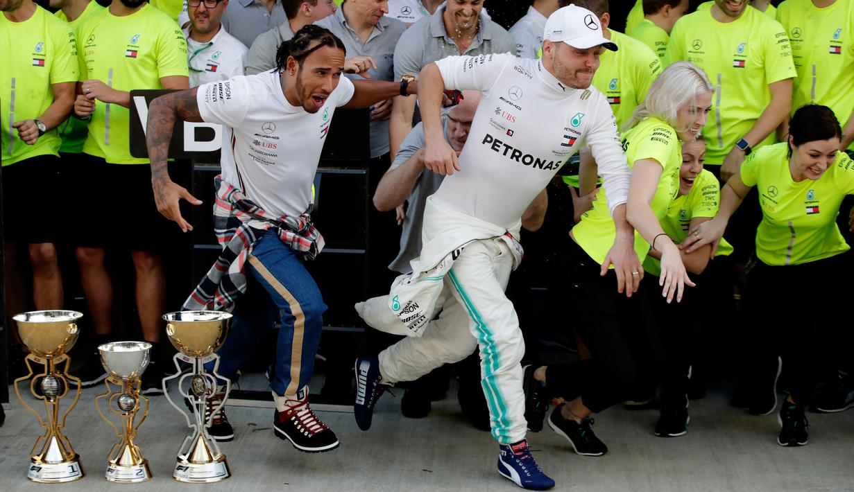 Pembalap Mercedes Lewis Hamilton dan rekan setimnya Valtteri Bottas berlari usai memenangkan F1 GP Rusia di Sochi Autodrom, Sochi, Minggu (29/9/2019). Hamilton dan Bottas finis di posisi pertama dan kedua. (AP Photo/Luca Bruno)