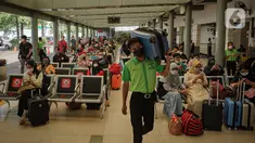 Petugas membawa koper melewati calon penumpang yang sedang menunggu keberangkatan kereta di Stasiun Pasar Senen, Jakarta, Jumat (24/12/2021). H-1 libur Natal dan Tahun Baru, peningkatan penumpang kereta jarak jauh mulai terlihat dengan tujuan sejumlah kota di Pulau Jawa. (Liputan6.com/Faizal Fanani)