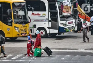 Pemudik membawa barang mereka seusai turun dari bus antarkota antarprovinsi (AKAP) di Terminal Kampung Rambutan, Jakarta, Minggu (23/5/2021). Hingga sore ini pemudik dari kota di Jawa Barat, Tengah, Timur, dan Sumatera terus berdatangan di Terminal Kampung Rambutan. (merdeka.com/Iqbal S Nugroho)