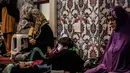 Seorang anak laki-laki bermain telepon ketika ibunya dan para wanita Muslim lainnya berdoa pada malam pertama salat tarawih di Masjid Nizamiye di Midrand, Johannesburg, Afrika Selatan (16/5). (AFP Photo/Gulshan Khan)