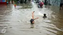 Seorang anak asyik bermain banjir yang merendam kawasan Benhil RT 03 RW 05, Jakarta Pusat, Selasa (21/1). Hujan deras yang mengguyur sejak Selasa dinihari mengakibatkan kawasan tersebut mengalami banjir. (Liputan6.com/Johan Tallo)