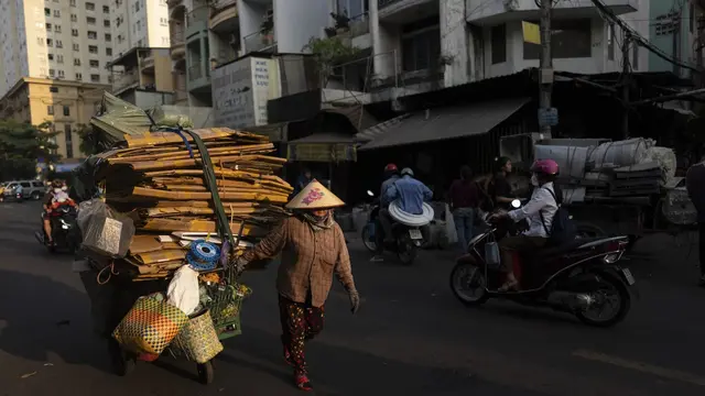 Seorang wanita menarik gerobak penuh karton untuk didaur ulang saat matahari terbenam di Kota Ho Chi Minh, Vietnam, Rabu, 31 Januari 2024. (AP Photo/Jae C. Hong)