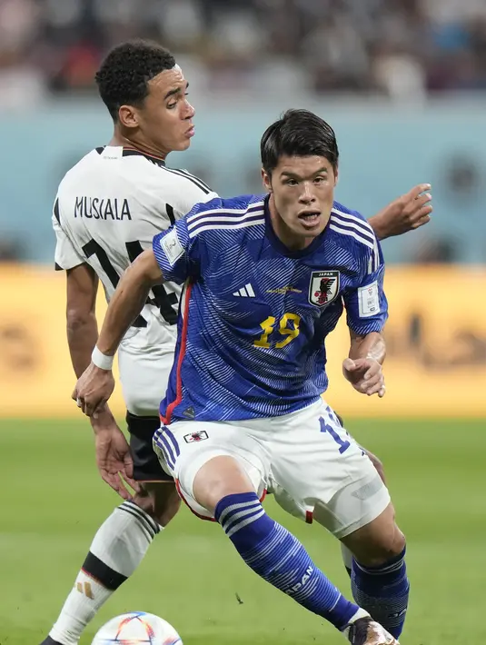 Bek Jepang, Hiroki Sakai melewati penyerang Jerman, Jamal Musala selama pertandingan grup E Piala Dunia 2022 Qatar di Stadion Internasional Khalifa di Doha, Qatar, Rabu (23/11/2022). Jepang menang tipis atas Jerman dengan skor 2-1. (AP Photo/Luca Bruno)
