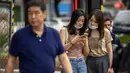 Dua perempuan melihat smartphone saat mereka berdiri di sudut jalan di Beijing, Rabu (6/7/2022). Warga beberapa bagian Shanghai dan Beijing telah diperintahkan untuk menjalani tes massal COVID-19 lebih lanjut menyusul ditemukannya kasus baru di dua kota, sementara pembatasan tambahan tetap berlaku di Hong Kong, Makau, dan kota-kota lain. (AP Photo/Mark Schiefelbein)
