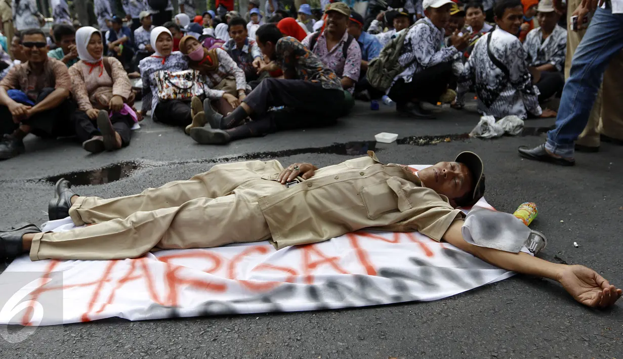 Seorang guru terlihat tidur di tengah jalan karena lelah usai melakukan unjuk rasa di depan Gedung DPR/MPR, Jakarta, Selasa (15/9/2015). Ribuan guru honorer melakukan aksi demo menuntut perubahan status honorer K2 menjadi PNS. (Liputan6.com/Yoppy Renato)
