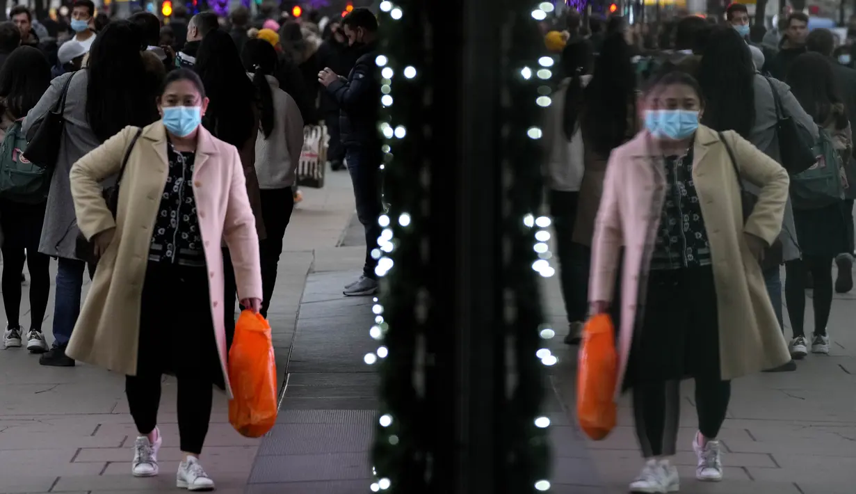 Pembeli terpantul di jendela saat mereka berjalan di Oxford Street, jalan perbelanjaan tersibuk di Eropa, di London, Kamis (23/12/2021). Meskipun pandemi covid-19, salah satu pusat perbelanjaan di London tersebut begitu ramai menjelang Natal. (AP Photo/Frank Augstein)