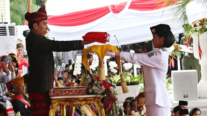 Presiden Jokowi menyerahkan Bendera Merah Putih kepada Fariza Putri Salsabila, anggota Pasukan Pengibar Bendera Pusaka (Paskibraka), saat Upacara Peringatan Detik-detik Proklamasi 17 Agustus di Istana, Jakarta, Kamis (17/8). (/Pool)