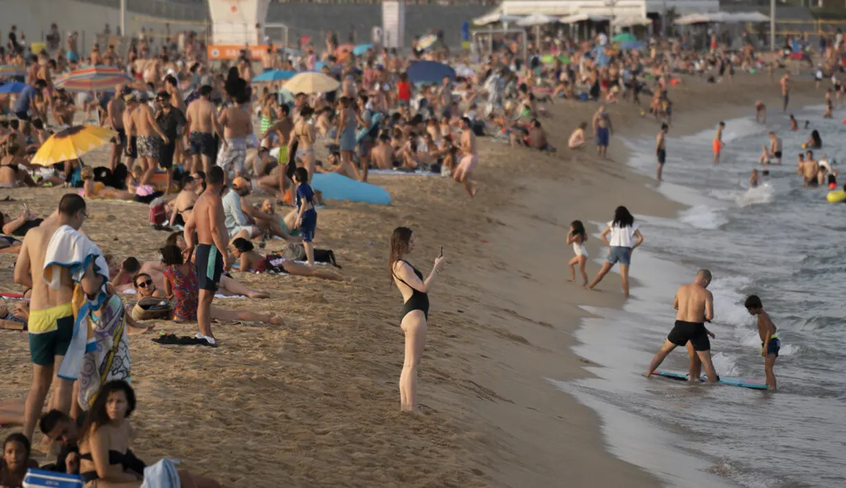 Seorang wanita mengambil foto saat menikmati cuaca panas di pantai di Barcelona, Spanyol, Kamis (12/8/2021). Layanan cuaca nasional Spanyol memperingatkan suhu bisa mencapai 44 derajat Celcius (111 derajat Fahrenheit) di beberapa daerah dalam beberapa hari mendatang. (AP Photo/Joan Mateu Parra)