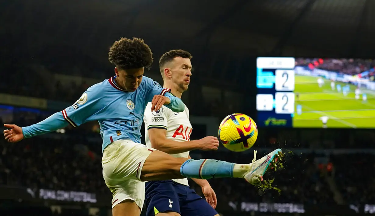 Pemain Manchester City Rico Lewis (kiri) menendang bola melewati pemain Tottenham Hotspur Ivan Perisic pada pertandingan sepak bola Liga Inggris di Etihad Stadium, Manchester, Inggris, 19 Januari 2023. Manchester City mengalahkan Tottenham Hotspur dengan skor 4-2. (AP Photo/Dave Thompson)