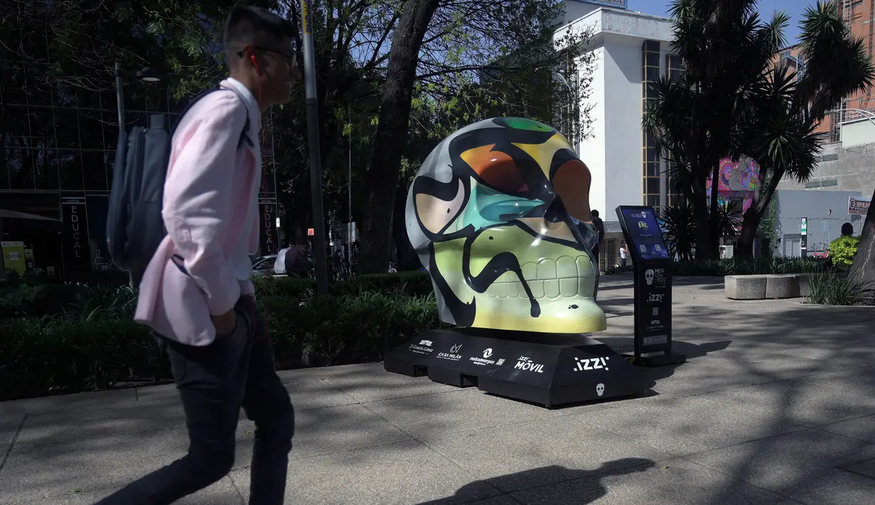 Seorang pria melewati tengkorak yang dihias selama pameran edisi keempat "Mexicraneos" (Mexisculls) di Reforma Avenue, Mexico City pada 23 Oktober 2020. Pameran tersebut karya seniman dari berbagai bagian negara Meksiko, dan juga dari Amerika Serikat serta Venezuela. (ALFREDO ESTRELLA/AFP)
