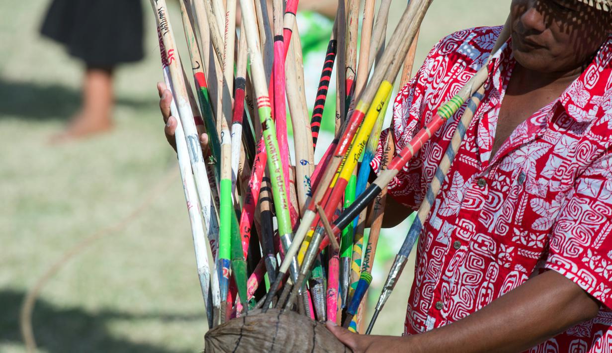 Seorang pria menunjukkan lembing yang menancap pada kelapa saat kompetisi panjat pohon kelapa di Papeete, Polinesia (15/7). Kompetisi ini diikuti peserta hingga kepulauan di Samudera Pasifik, Hawaii dan Kepulauan Samoa. (AFP Photo/Gregory Boissy)