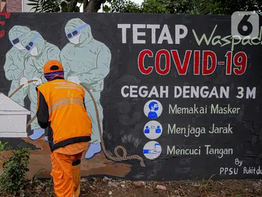 Petugas PPSU Kelurahan Bukit Duri menyelesaikan mural bertema Covid-19 di Jakarta, Selasa (11/8/2020). Mural tersebut untuk mengingatkan warga agar selalu waspada dengan Covid-19 dan mencegahnya dengan 3M (Memakai Masker, Menjaga Jarak dan Mencuci Tangan). (Liputan6.com/Faizal Fanani)