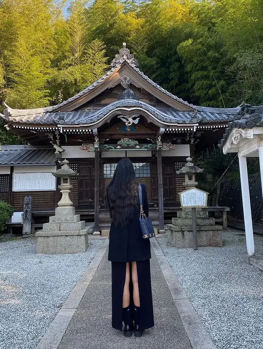 Dua Lipa mengenakan blazer hitam tanpa inner dengan rok panjang berwarna senada. Rok ini memiliki potongan tinggi di bagian belakang. [instagram/dualipa]