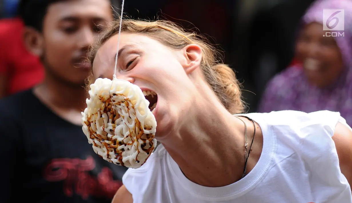 Salah satu warga negara asing saat mengikuti lomba makan kerupuk di kawasan Jalan Jaksa, Jakarta, Kamis (17/8). Lomba diadakan untuk memeriahkan HUT RI ke-72. (Liputan6.com/Helmi Fithriansyah)