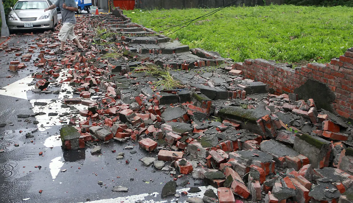 Seorang pria berjalan di antara reruntuhan batu bata sebuah dinding yang hancur akibat Topan Matmo, Taiwan, Rabu (23/7/14). (REUTERS/Pichi Chuang)