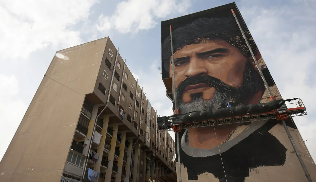 Mural legenda sepak bola, Diego Armando Maradona yang digambar di sebuah tembok pemukiman warga di San Giovanni a Teduccio, Italia (28/2). Jorit Agoch dikenal sebagai seniman mural hyper-realistis. (AFP/Renato Esposito)