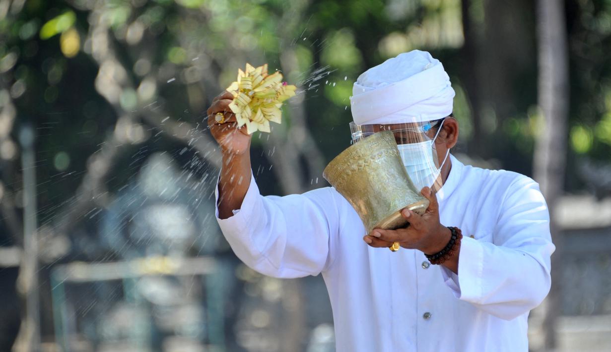 Pemuka Agama Hindu memercikkan air suci saat upacara Melasti menjelang Hari Raya Nyepi Tahun Baru Saka 1943 di Pantai Kuta, Bali (11/3/2021). Ritual Melasti untuk menyucikan alam agar Hari Raya Nyepi dapat berjalan  hening serta damai. (AFP/Sonny Tumbelaka)
