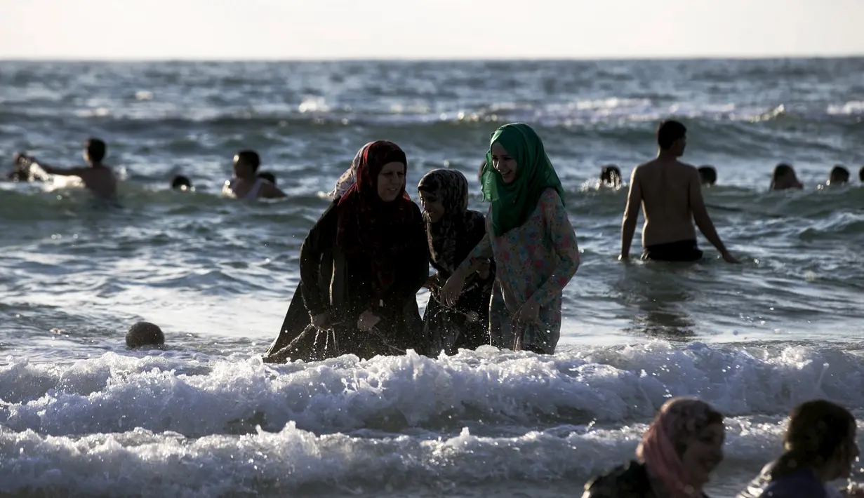 Sejumlah wanita Muslim bermain air di pantai Tel Aviv, Israel, Minggu (19/7/2015). Selama Idul Fitri, pemerintah Israel mengizinkan warga Palestina untuk berwisata di sepanjang garis pantai Mediterania. (REUTERS/Baz Ratner) 