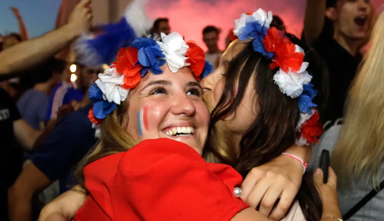 Warga saling berpelukan saat peluit akhir pertandingan antara Prancis dengan Belgia pada semifinal Piala Dunia 2018, Marseille, Prancis, Selasa (10/7). Prancis menaklukkan Belgia dan maju ke babak final. (AP Photo/Claude Paris)