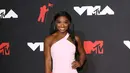 Penampilan Simone Biles di MTV Video Music Awards tahun 2021, mengenakan gaun merah muda pastel dengan garis leher asimetris dan high slit, kontras dengan gold hoops dan heels beningnya. [Foto: InStyle]