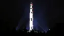 Orang-orang menyaksikan proyeksi roket NASA, Saturn V, di Monumen Washington menandai peringatan 50 tahun misi Apollo 11 ke bulan di National Mall, Washington, Selasa (16/7/2019). Pada 16 Juli 1969, NASA mencatatkan sejarah dengan melakukan peluncuran Apollo 11. (Mark Wilson/Getty Images/AFP)