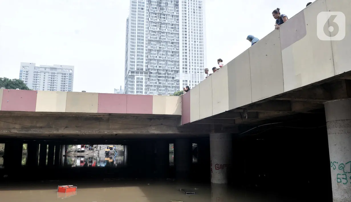 Warga melihat kondisi underpass Kemayoran yang masih terendam bajir di Jakarta Pusat, Minggu (26/1/2020). Banjir yang terjadi sejak Jumat (24/1) lalu hingga kini belum surut. (merdeka.com/Iqbal S Nugroho)