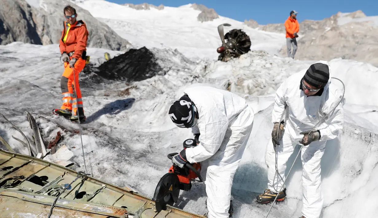 Anggota tentara Swiss memotong bagian pesawat tempur Perang Dunia II milik AS saat ditemukan di Gauli Glacier, di Bernese Alps, Swiss (17/9). Pesawat Perang Dunia II C-53 Skytrooper Dakota tersebut jatuh tahun 1946. (Peter Klaunzer/Keystone via AP)