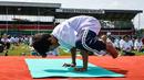 Seorang anak lelaki melakukan gerakan yoga saat mengikuti yoga massal di Stadion Afraha, Nakuru, Kenya (15/6/2019). Hari Yoga Internasional, yang setiap tahun dirayakan pada 21 Juni, pertama kali diusulkan Perdana Menteri India Narendra Modi pada 2014 ke Majelis Umum PBB. (AFP Photo/Suleiman Mbatiah