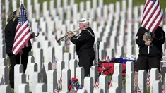 Pensiunan Angkatan Laut Amerika Serikat Yeoman Mark Stallins memainkan Taps untuk keluarga prajurit yang gugur di sebuah kuburan di Pemakaman Nasional Fort Logan, Sheridan, Colorado, Amerika Serikat, 30 Mei 2022. (AP Photo/David Zalubowski)