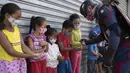 Polisi militer Everaldo Pinto, berkostum Captain America, menyemprotkan cairan pembersih ke tangan anak-anak di Petropolis, Brasil, Kamis (15/4/2021). Dalam aksinya, Pinto membagikan kotak berisi produk pembersih dan masker untuk mencegah paparan corona pada anak-anak. (AP Photo/Silvia Izquierdo)